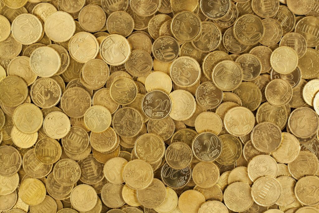 A close-up shot of Euro coins scattered in a pile, showcasing a rich golden texture.