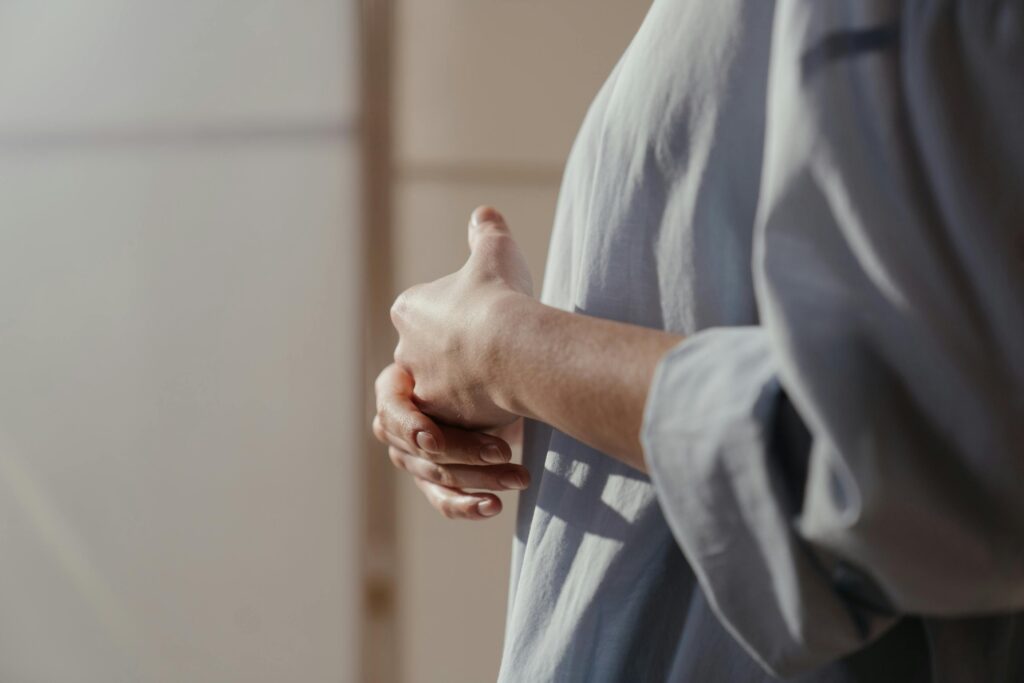 Close-up of hands showing contemplation and emotion in a soft light setting.
